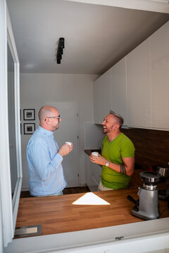 Gay couple talking and having coffee in the kitchen
