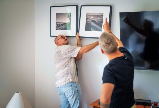 Gay partners putting up pictures on the wall in their new home