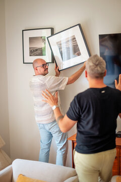 Gay partners putting up pictures on the wall in their new home
