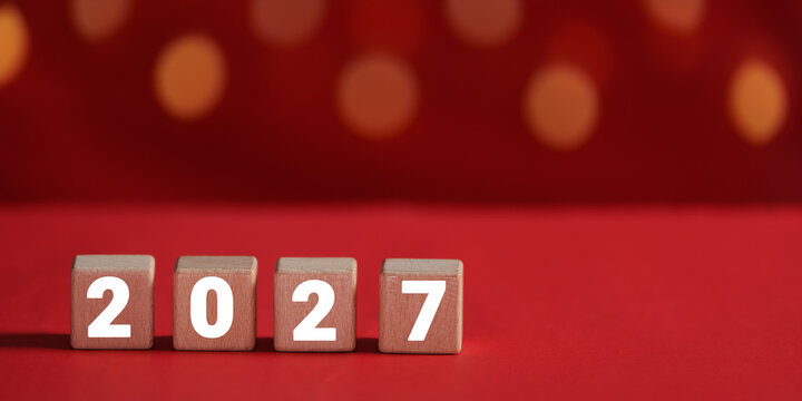 Wooden blocks spelling 2027 on red bokeh background for New Year celebration