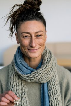 Closeup portrait of a smiling freckled woman holding a key while wearing layered scarves for lifestyle background and banner design