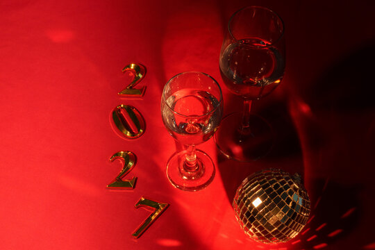 Golden 2027 numbers with wine glasses and disco ball for New Year celebration