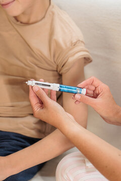 Mother giving her son an injection with a pen at home