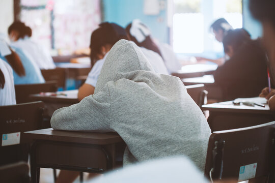 Exhausted Student Sleeping on Desk During Final Exam in Classroom