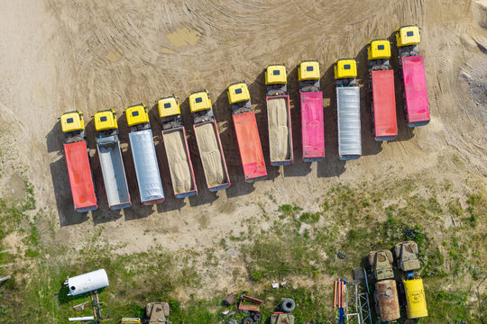Aerial view of a sand and gravel mine with a row of parked dump trucks loaded with sand and gravel in Masovian Voivodeship, Poland.