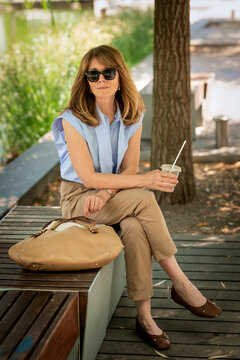 A middle-aged woman sitting on a bench in a city park