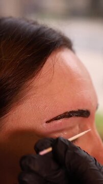 Macro close up of eyebrow threading with black gloves and wooden tool