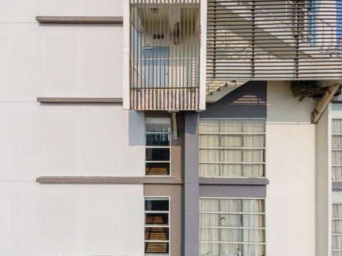 Aerial view of a modern building facade featuring a prominent balcony structure with vertical louvers, clean geometric lines, and large windows in Purwokerto, Central Java, Indonesia.
