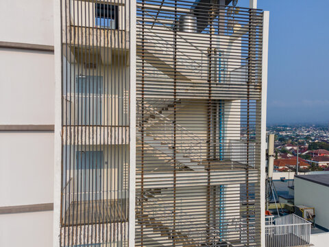 Aerial view of a modern building facade featuring a metal louvered staircase enclosure with visible stairs and doors in Purwokerto, Central Java, Indonesia.