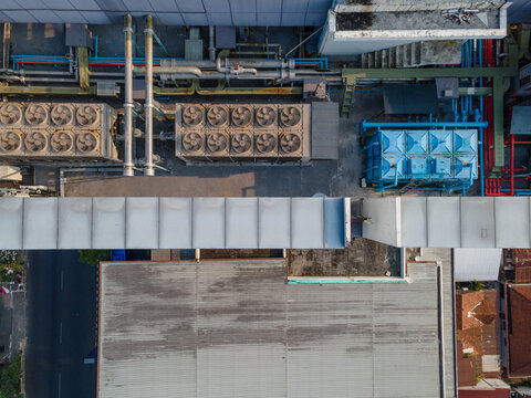Aerial view of industrial rooftop featuring large HVAC cooling units, complex piping systems, and ventilation ducts in Purwokerto, Central Java, Indonesia.