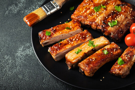 Hot grilled spare ribs from a summer BBQ served on a plate with sauce. Top view. Copy space