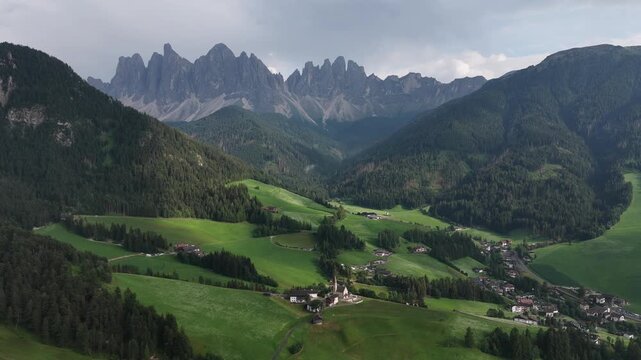 serene rural valley with mountains in the background, aerial perspective of grassy meadows and rocky terrain, houses nestled among nature, peaceful landscape for travel and nature scenes.