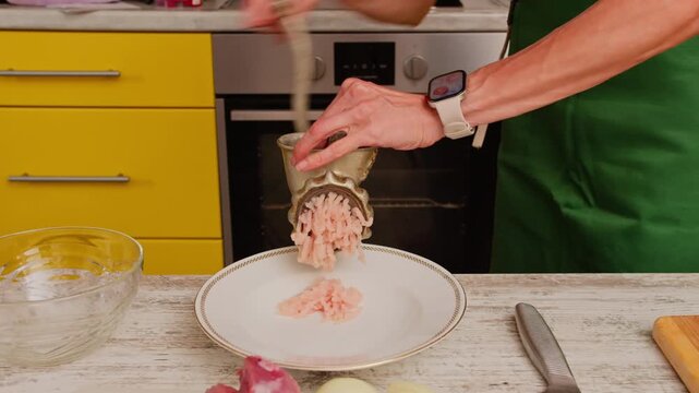 Woman using manual meat grinder in home kitchen. Preparing ingredients for homemade meals following traditional recipes