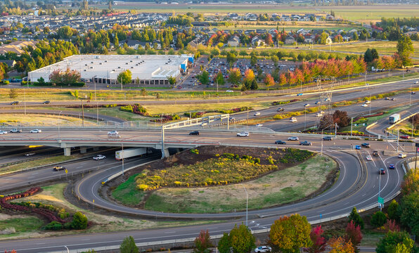 Aerial view of the Interstate 5 highway interchange with multi-level ramps, flowing traffic, and suburban landscape with autumn foliage in Woodburn, Oregon, United States.
