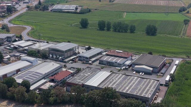 Drone view of an industrial logistics area with warehouses, production buildings, parked trucks and solar panels installed on rooftops. Useful for logistics, distribution, freight and supply chain sto