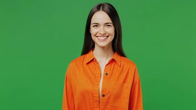 Young woman in orange shirt smiling and winking with a green screen background and subtle camera zoom