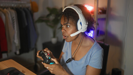 Young woman playing gamepad with headset, mouth open and focused at computer desk in studio  competitive excitement. © Krakenimages.com