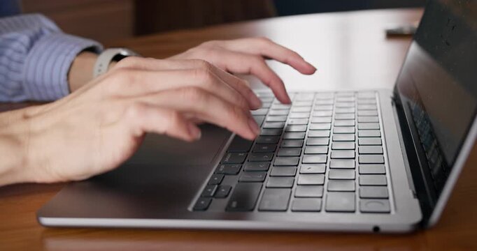 Close-up of woman typing on laptop at table while working from home. Freelance work from home.