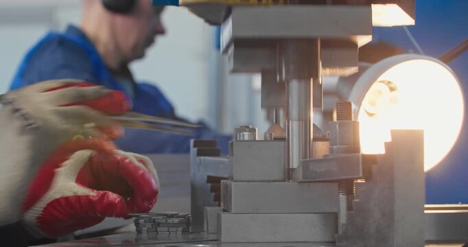 Blue collar machine operator at work on mechanical press during metal parts bending. Factory production and industrial metalworking, close-up