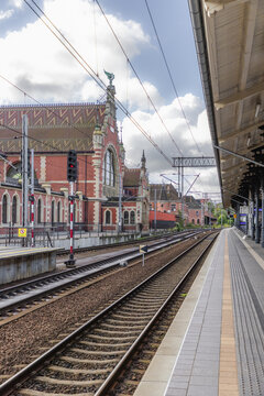 Gdansk, Poland - 06 September 2026: View of the historic Gdansk Glowny railway station with its red brick facade, clock tower, and tracks along the platform under a cloudy sky.