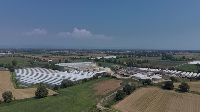 Aerial view of a large agricultural operation combining cattle farming, vegetable greenhouses, renewable energy systems and biomethane production in northern Italy.