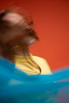 Woman in yellow dress veiled by flowing blue fabric
