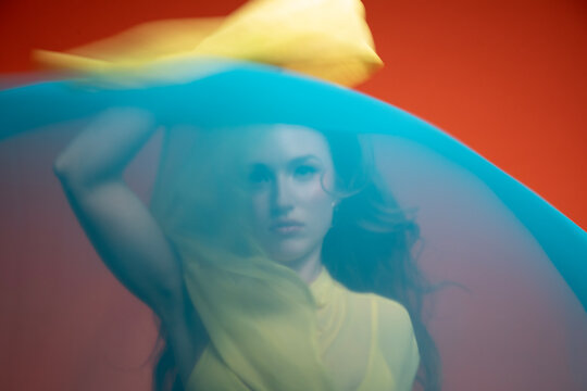 Woman in a yellow dress veiled by flowing blue fabric