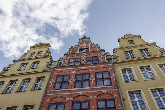 View of historic colorful townhouses with ornate gables and multi-pane windows under a blue sky in Gdansk, Pomeranian Voivodeship, Poland.