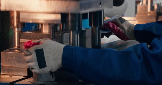 Close-up of factory work at mechanical punch press. Machine operator engaged in metal blanking, illustrating blue collar employment in manufacturing