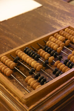View of a traditional wooden abacus with rows of light brown and black beads resting on a rustic wooden table in Gdansk, Pomeranian Voivodeshi, Poland.