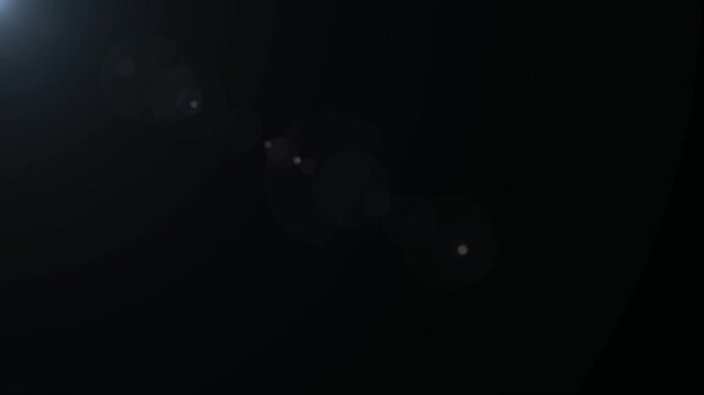 Subtle lens flare shines brightly in the corner of a dark empty background creating a minimalist lighting effect with plenty of space.