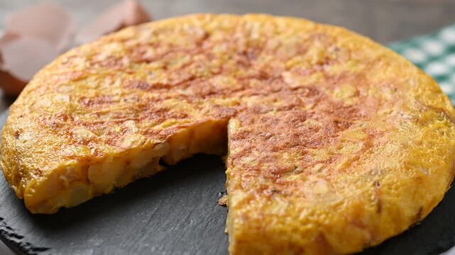 Close-up video of a traditional Spanish tortilla rotating on a plate, showing its golden surface and homemade texture. Classic potato and egg omelette from Spanish cuisine.