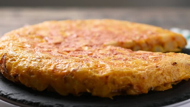 Close-up video of a traditional Spanish tortilla rotating on a plate, showing its golden surface and homemade texture. Classic potato and egg omelette from Spanish cuisine.