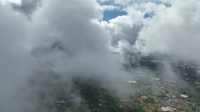 Airplane flying through clouds above rural landscape in South Korea