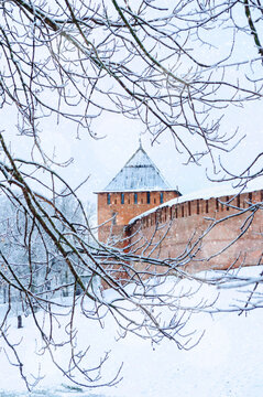Veliky Novgorod Russia, Vladimir tower of Kremlin fortress seen through dark frosted branches with falling snowflakes, winter view