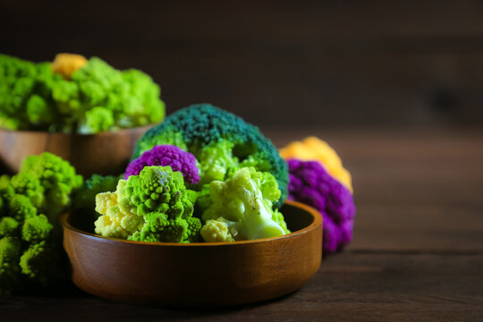 Multicolored cauliflower on a wooden table. Purple, yellow, and green florets. Rustic still life.