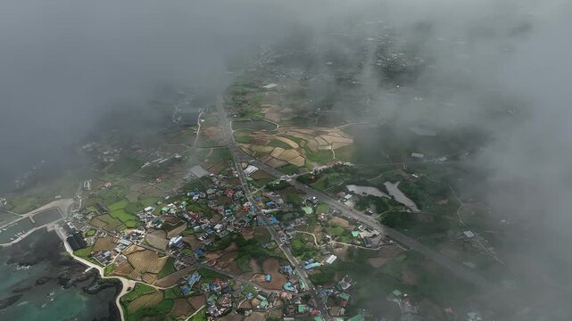 Aerial view flying through clouds above coastal village, South Korea