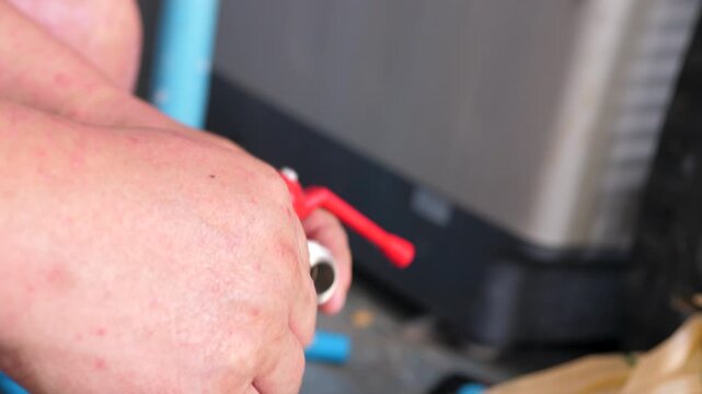 Close up hands of man applying PTFE thread seal tape to a water valve before plumbing installation
