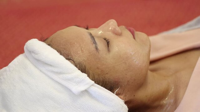 Close-up of young Asian woman receiving facial treatment with electronic beauty device in spa