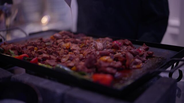 Professional chef cooking savory meat and vegetables on a hot flat top grill in a restaurant