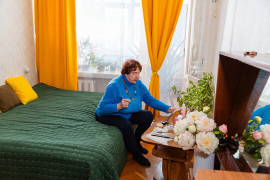 Senior Caucasian woman using beauty products as part of everyday self care. Sitting comfortably at home, the grandmother focuses on appearance, confidence, femininity, and healthy aging. Top view