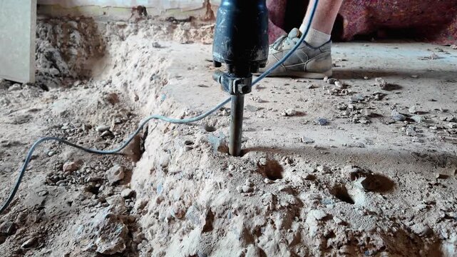 Rotating view of jackhammer breaking up a concrete floor in a house renovation