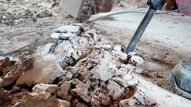Hammer drill chipping away the edge of a concrete slab during renovation