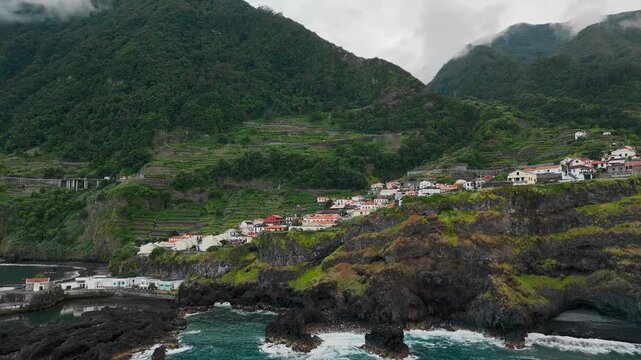 Seixal village and terraced hillsides in Madeira, Portugal, aerial view. Coastal settlement and farmland occupy steep terrain beside Atlantic Ocean