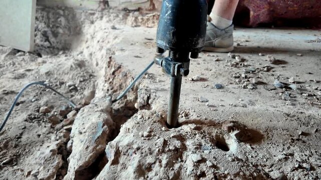 Orbiting close-up of demolition hammer chisel driving into concrete rubble