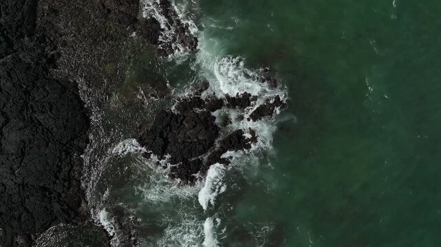 Aerial view of ocean waves crashing on volcanic coastline, South Korea