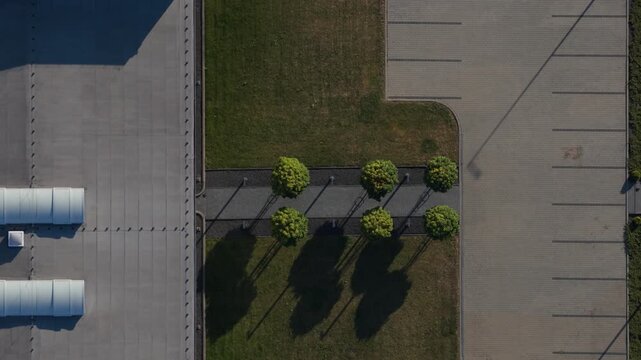 Aerial top-down view of empty parking lot and modern industrial building rooftop