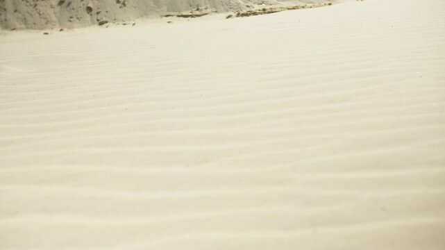 Strong wind blowing sand across rippled desert dunes creating a sandstorm in a beautiful arid landscape on a sunny day