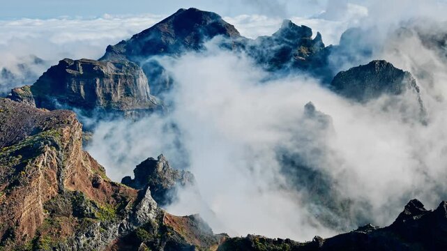 Rock pinnacle amid low clouds near Pico do Arieiro, Madeira, Portugal. Sheer mountain walls and narrow ridge above mist-filled ravines
