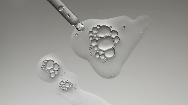 Cosmetic serum or gel with hyaluronic acid and bubbles dripping from a pipette on a gray background for skin care advertising